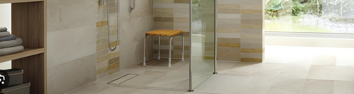 Level-access wet room with linear drain, glass screen and shower stool on a level tiled floor